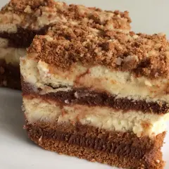 Pyszny deser z mascarpone i herbatnikami, z warstwami czekolady i kremu, posypany kruszonką.